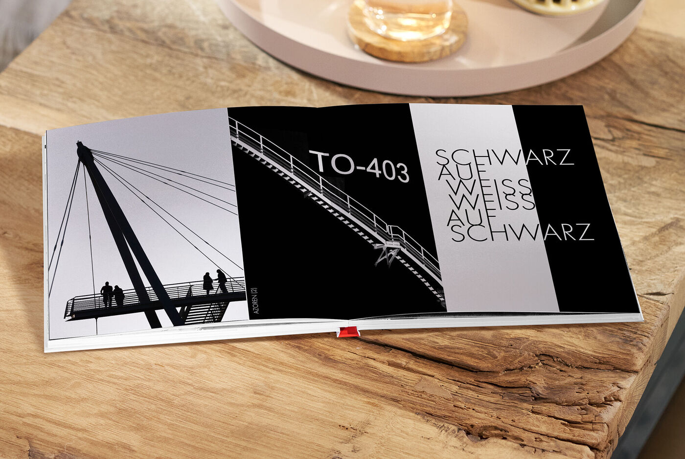 Offenes CEWE FOTOBUCH mit Fotos in Schwarz-Weiß von modernen Brücken auf einer Holzoberfläche