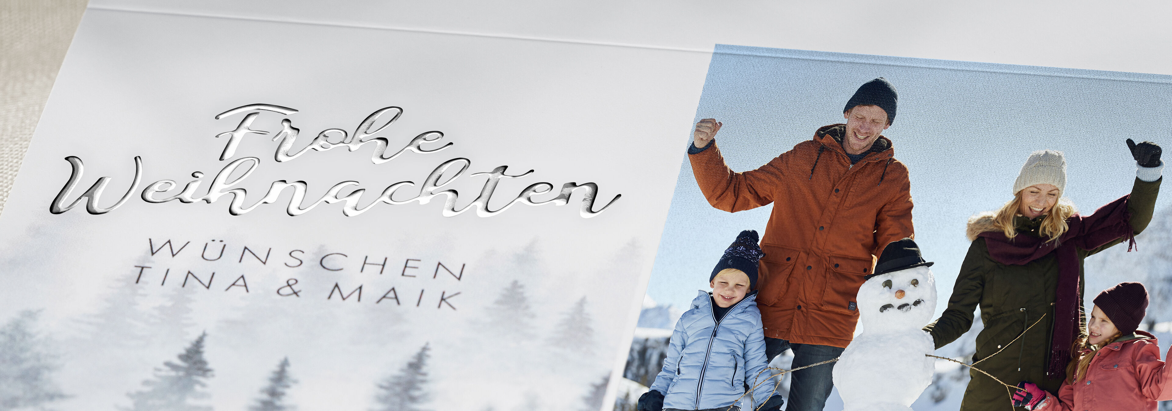 Familie feiert Weihnachten im Schnee mit Schneemann