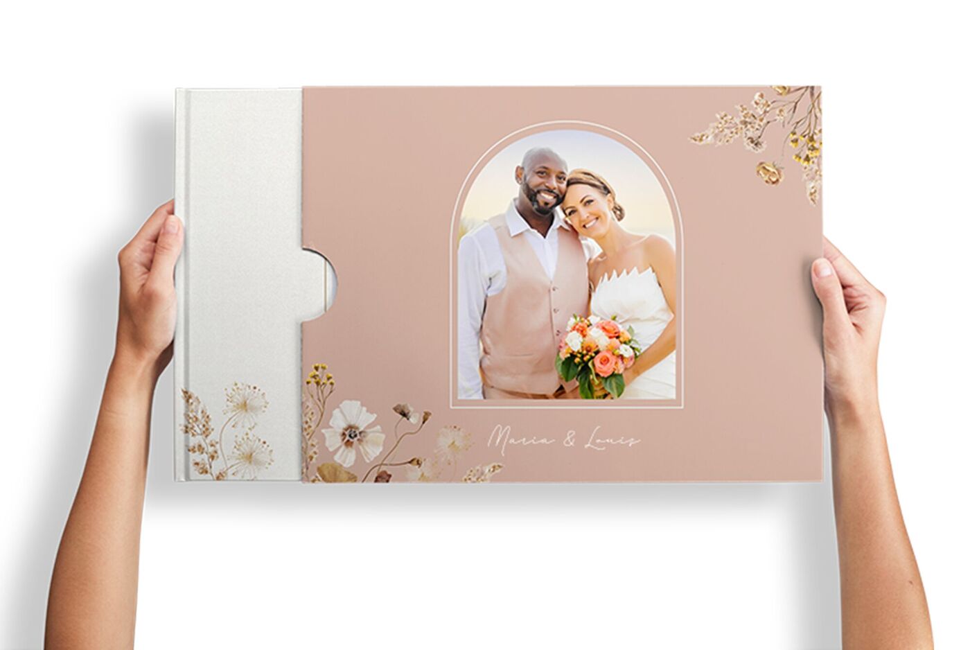 Hände halten ein CEWE FOTOBUCH zur Hochzeit mit zartem Blütendesign und Titelbild eines Paares