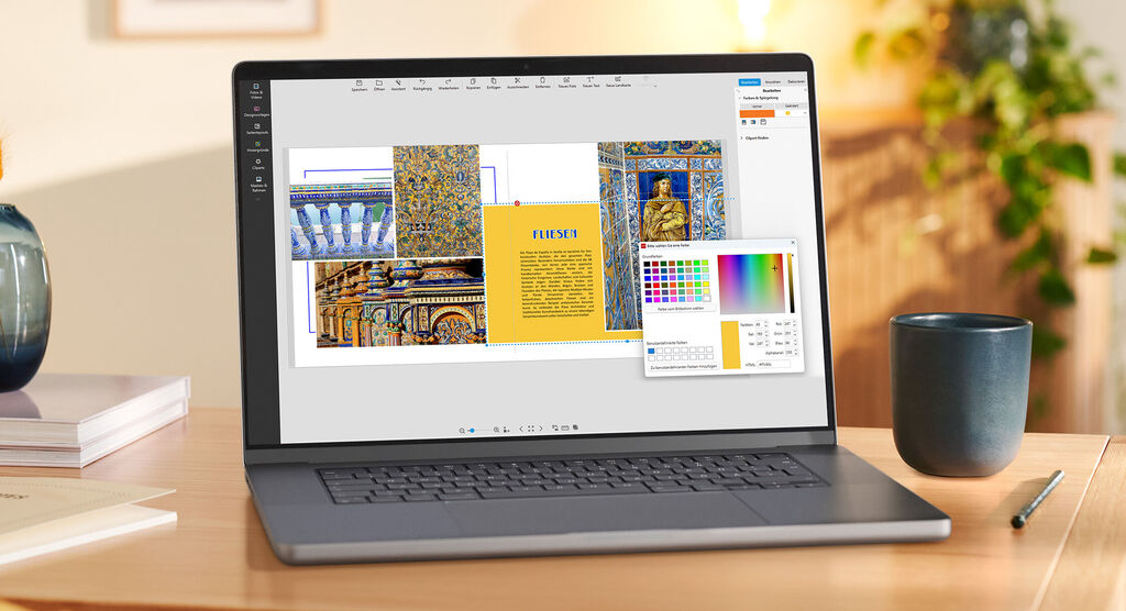 Ein Laptop steht auf einem Tisch. Auf dem Monitor ist die Gestaltungssoftware geöffnet. Fotos aus Andalusien sind zu sehen.