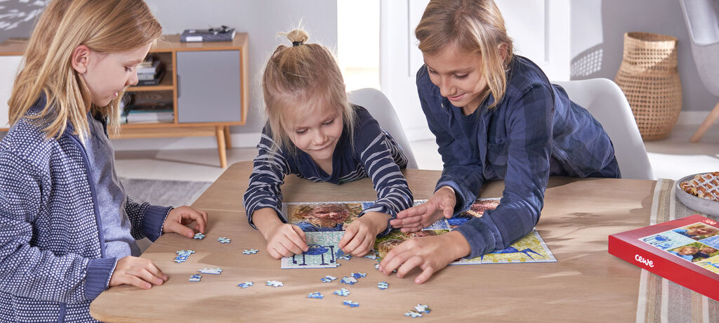 Drei Kinder konzentriert beim Puzzeln am Tisch