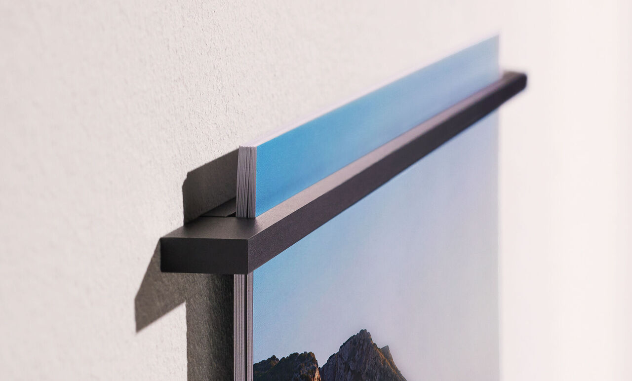 Detailaufnahme eines Wandbildes, das an einer Wand hängt und die obere Halterung zeigt