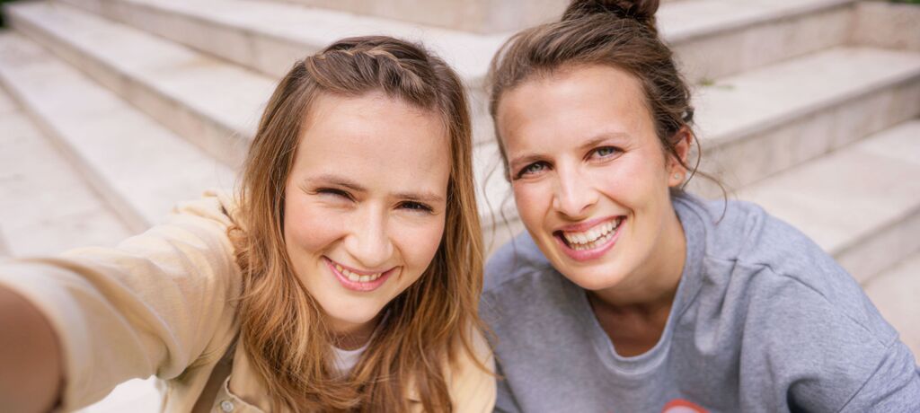 Zwei Frauen machen ein fröhliches Selfie auf einer Treppe