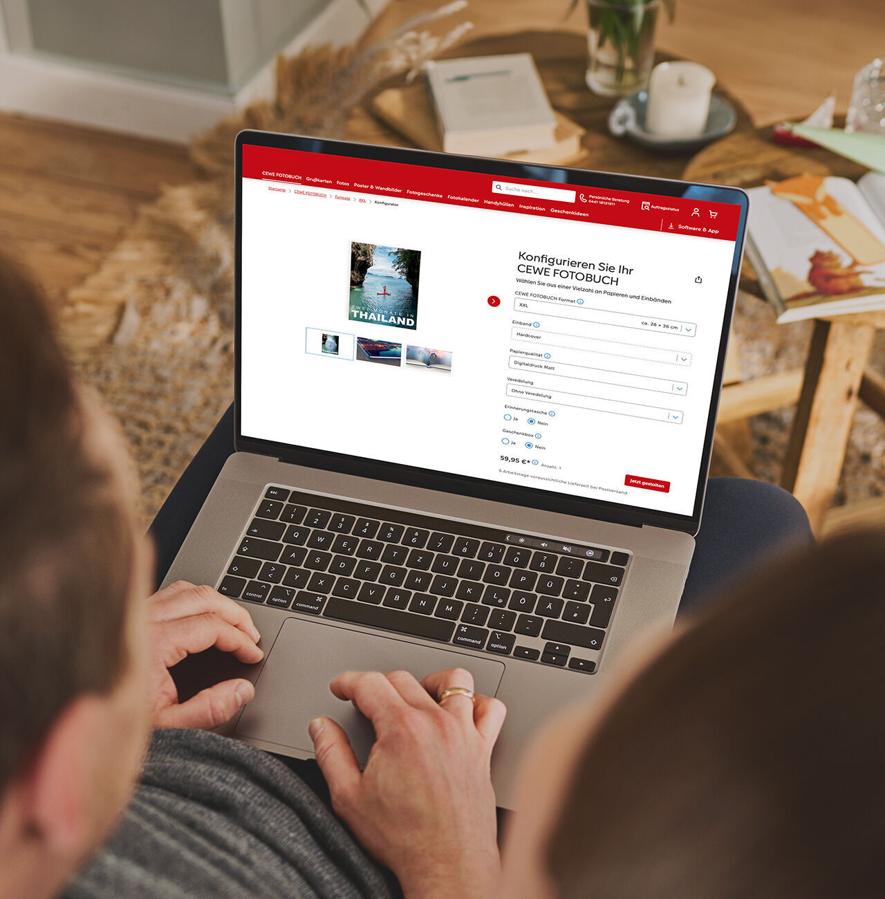 Eine Person sitzt mit einem Laptop auf dem Schoß und konfiguriert online ein CEWE FOTOBUCH.