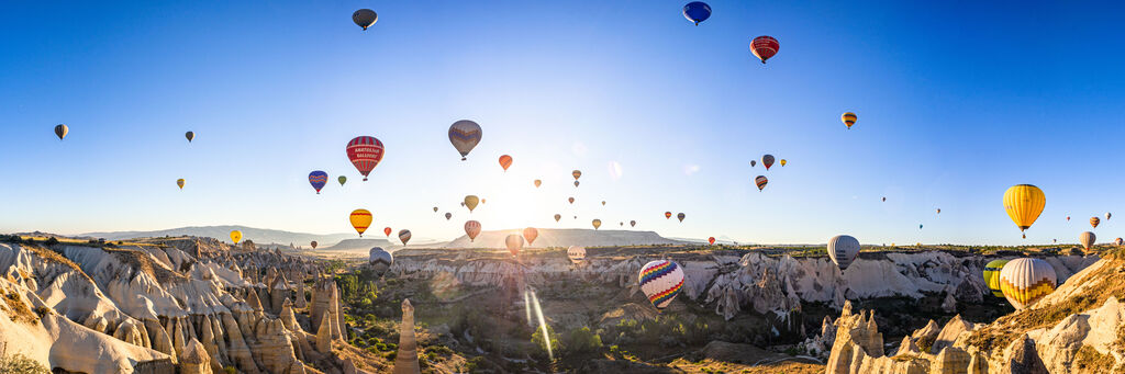 Bunte Heißluftballons steigen über der zauberhaften Landschaft von Kappadokien auf, unterhalb der warmen Sonnenstrahlen.