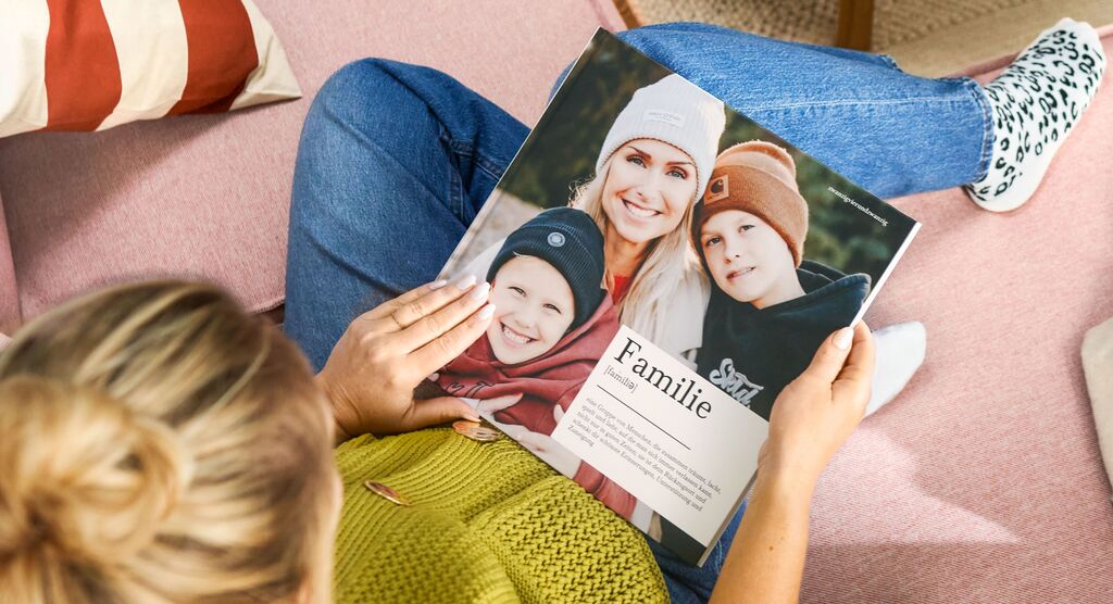 Eine Person liest das CEWE Fotobuch mit Bildern von der Familie.