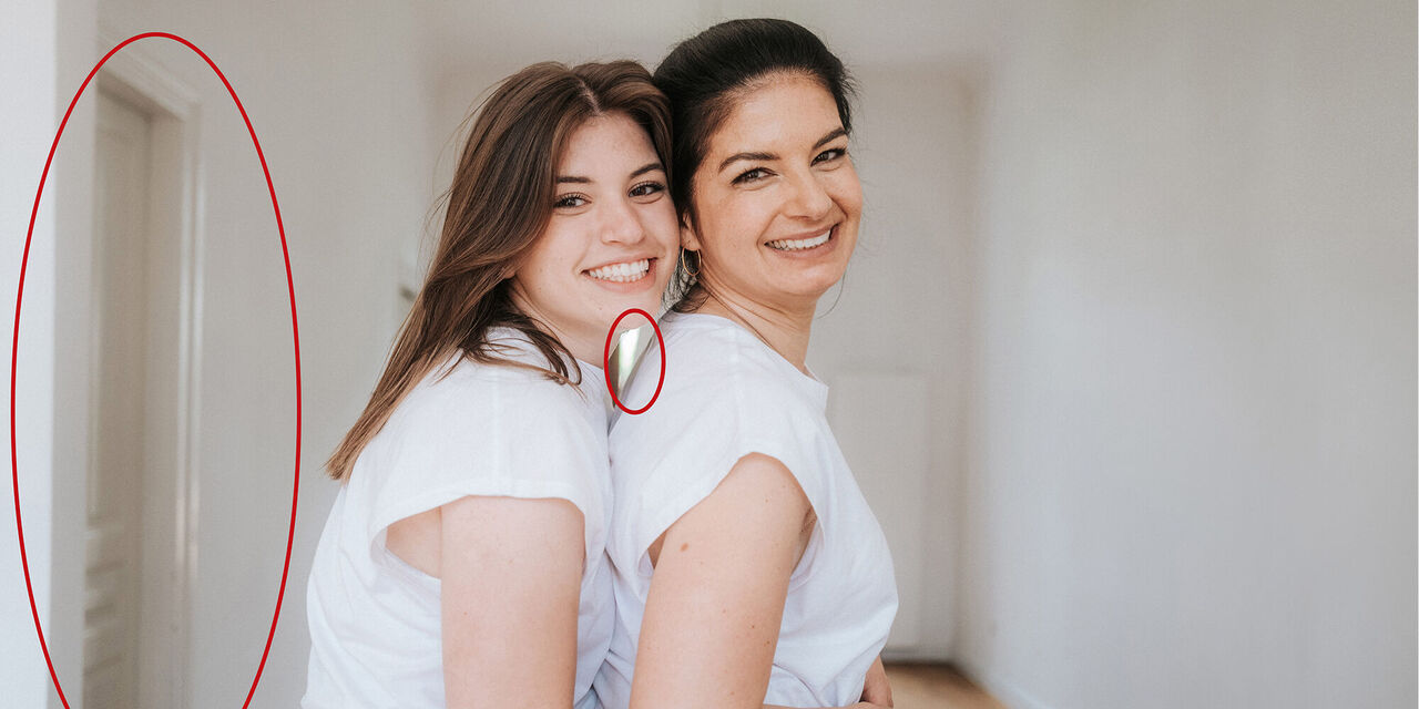 Zwei Frauen in weißen T-Shirts umarmen sich liebevoll in einem hellen Raum