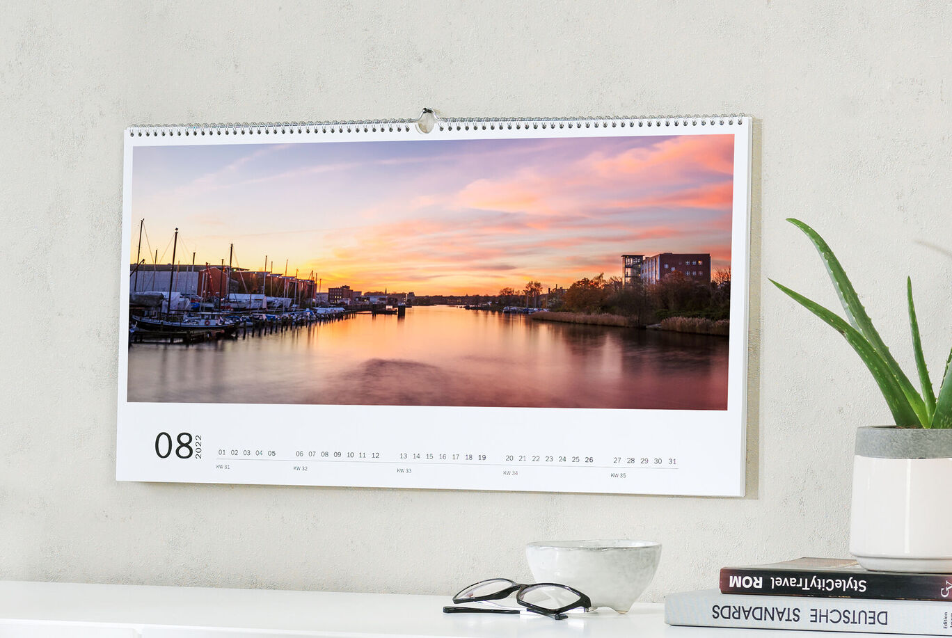 Ein wunderschöner Kalender mit einem Sonnenuntergang über einem ruhigen Wasserweg im August.