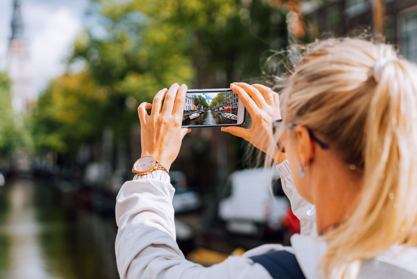 Frau fotografiert einen städtischen Kanal mit dem Smartphone.