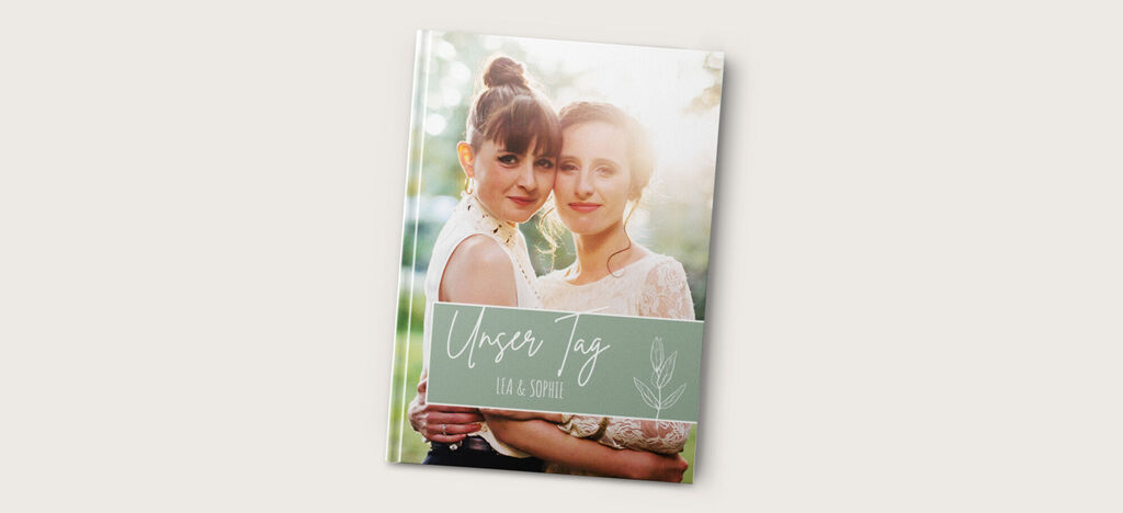Zwei Personen umarmend im Freien, umgeben von Natur. Emotionales Fotobuch mit dem Titel 'Unser Tag' auf dem Cover.