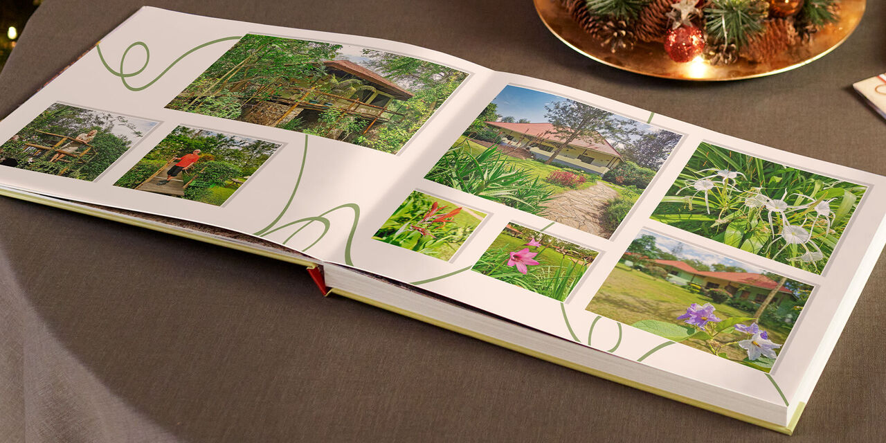 Offenes CEWE FOTOBUCH mit bunten Fotografien von Blumen und einem Garten auf einem Tisch.