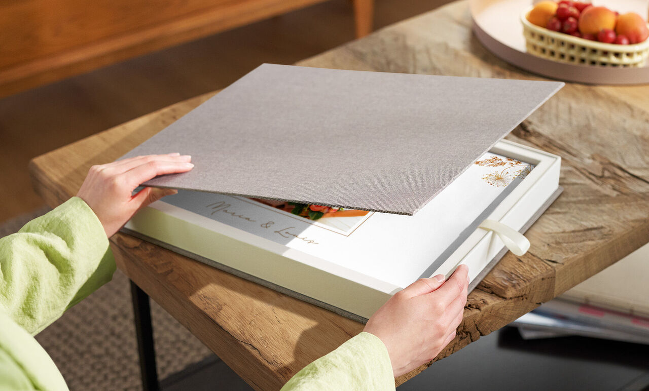 Person öffnet elegante Geschenkbox mit CEWE FOTOBUCH Hochzeit