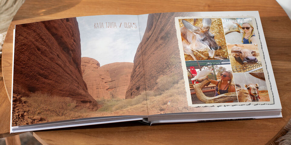 Ein offen liegendes Fotobuch mit bunten Bildern von Reisemomenten in der Natur und Tieren. Die Seiten sind kreativ gestaltet mit Fotos und Erinnerungen.
