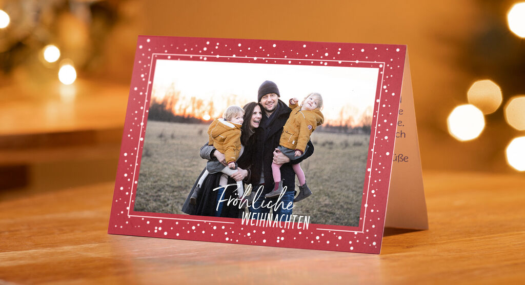 Rote CEWE Klappkarte mit Familienfoto bei Sonnenuntergang und Schrift Fröhliche Weihnachten