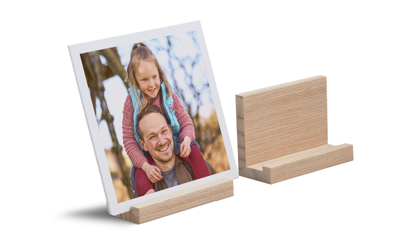 Ein Fotobild von einer sitzenden Person auf einem Holzständer, umgeben von grünen Bäumen. Das Bild strahlt Freude aus.