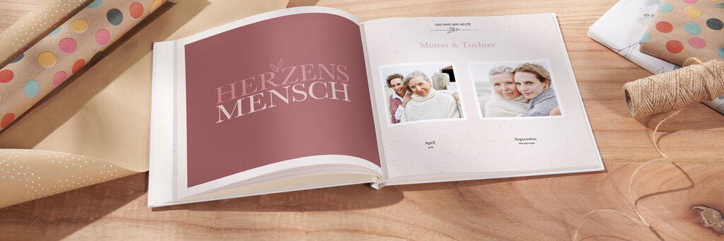 Ein offenes CEWE FOTOBUCH mit herzlichen Erinnerungen und liebevollen Fotos auf einem Tisch