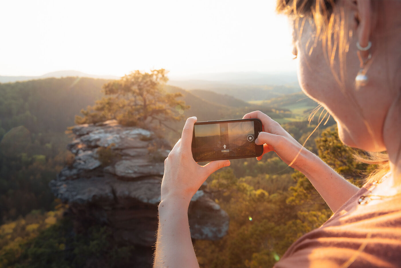 Frau fotografiert die Landschaft mit ihrem Smartphone