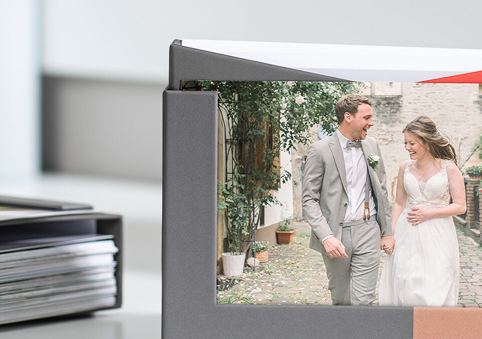 Ein Brautpaar in eleganten Hochzeitskleidern hält Händchen und läuft durch einen malerischen Garten.