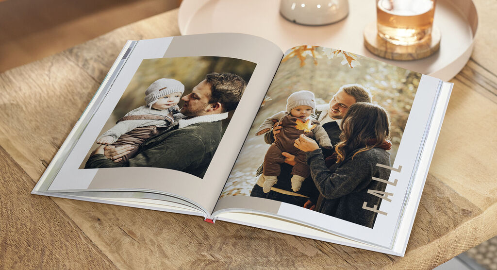 Ein offenes Fotobuch zeigt glückliche Familienmomente im Herbst.
