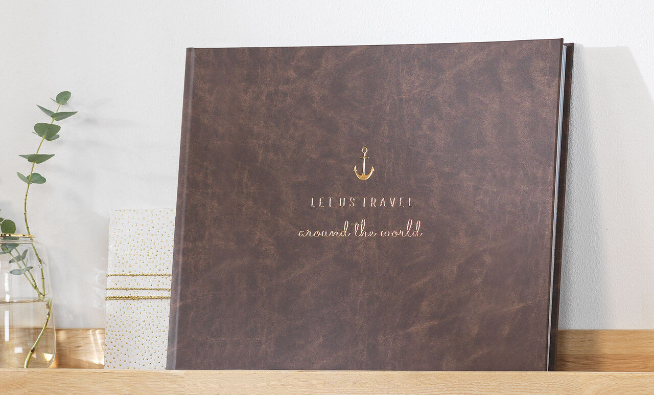 Braunes Fotobuch mit goldener Schrift auf dem Cover, liegt auf einem Regal