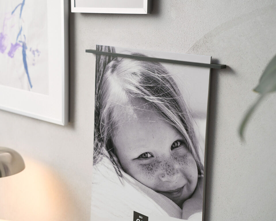 Schwarz-weißer CEWE Fotokalender hängt an einer hellen Wand neben einem gerahmten Bild.