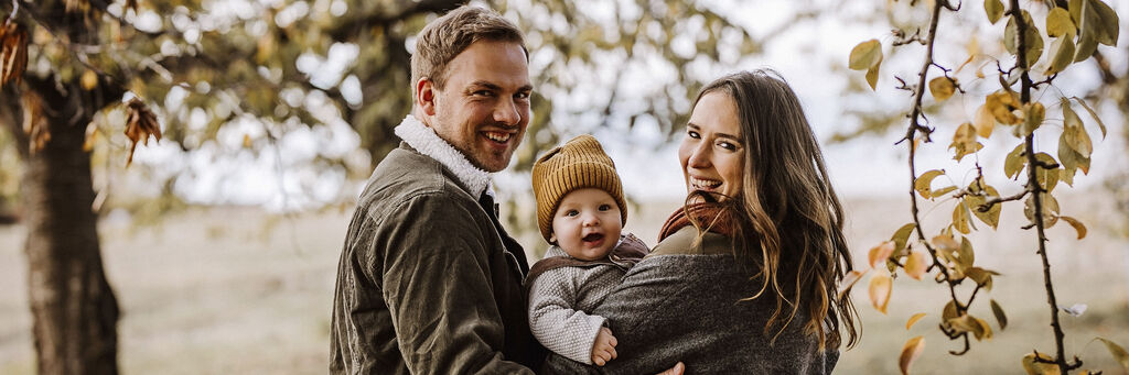 Eine Familie steht unter Bäumen und genießt die Zeit zusammen.