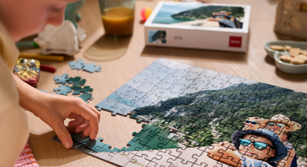 Ein Kind setzt Puzzlestücke zusammen mit einer Landschaft auf dem Bild.