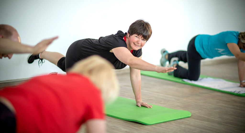 Eine Gruppe von Menschen übt auf Fitnessmatten.