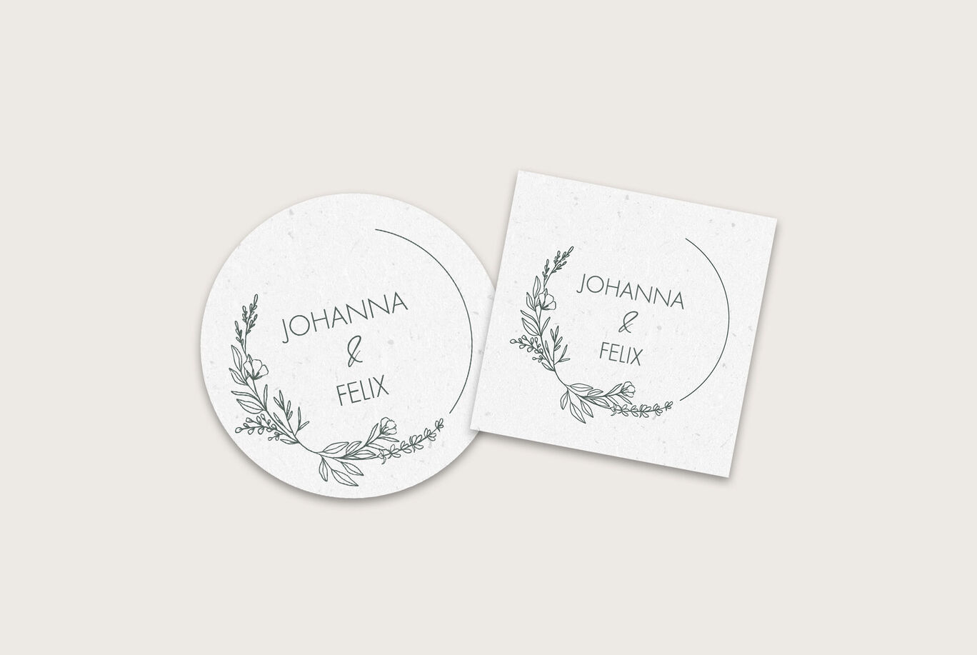 Ein Set mit zwei eleganten Einladungskarten, eine ovale und eine quadratische, mit den Namen Johanna und Felix in einer schönen Schrift umrahmt von zarten, floralen Motiven in Schwarz.