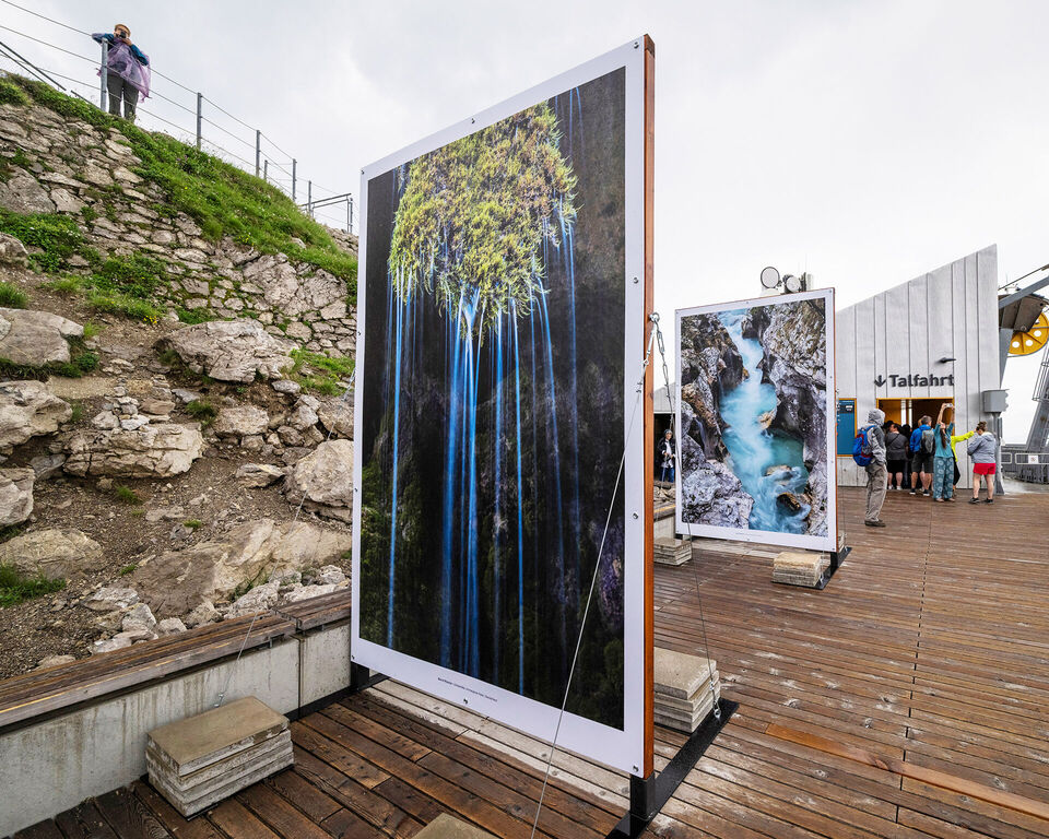 Auf einer Holzterrasse sind zwei große Leinwände mit verschiedenen Fotomotiven aufgestellt.
