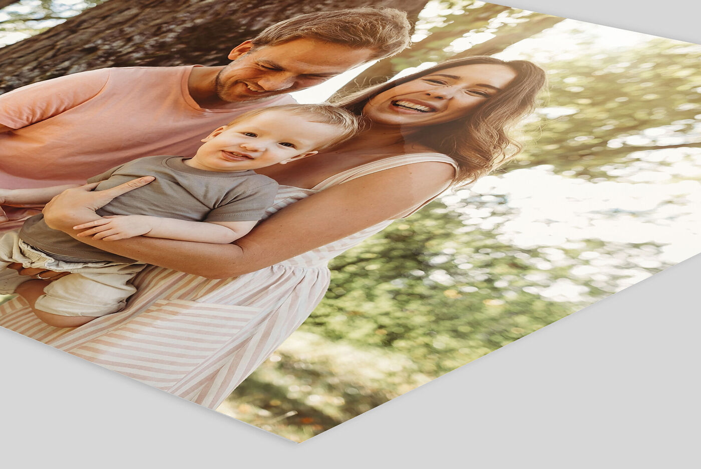 Eine fröhliche Familie im Freien, die zusammen lacht und eine schöne Zeit genießt. Ein Elternteil hält ein kleines Kind im Arm, während sie in die Kamera lächeln.