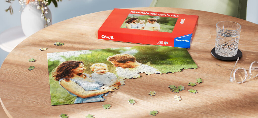 Familie mit Baby auf einem fast fertigen Puzzle, umgeben von Puzzlestücken