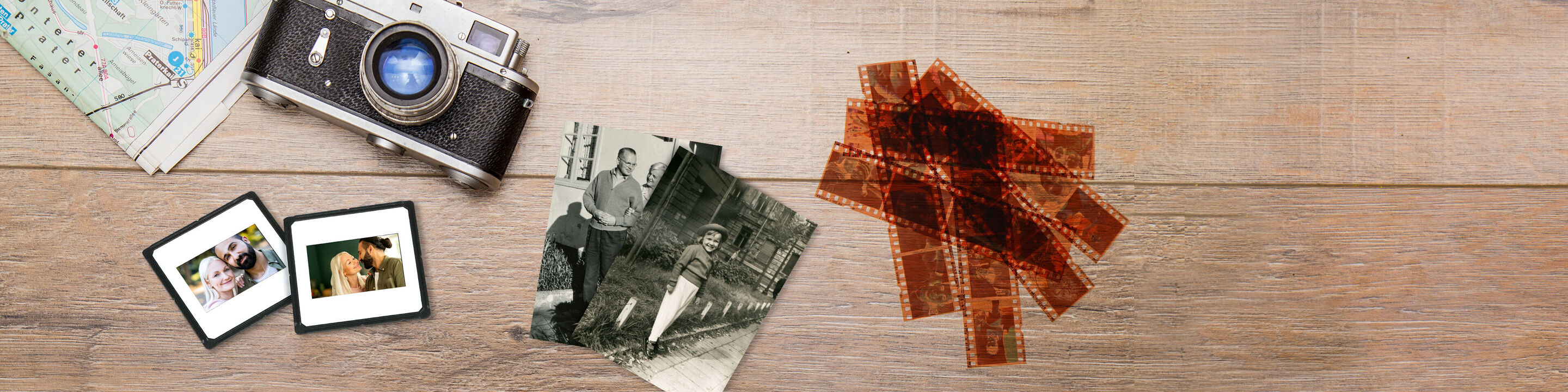 Ein Holztisch mit einem alten Fotoapparat, alten Fotos und Negative