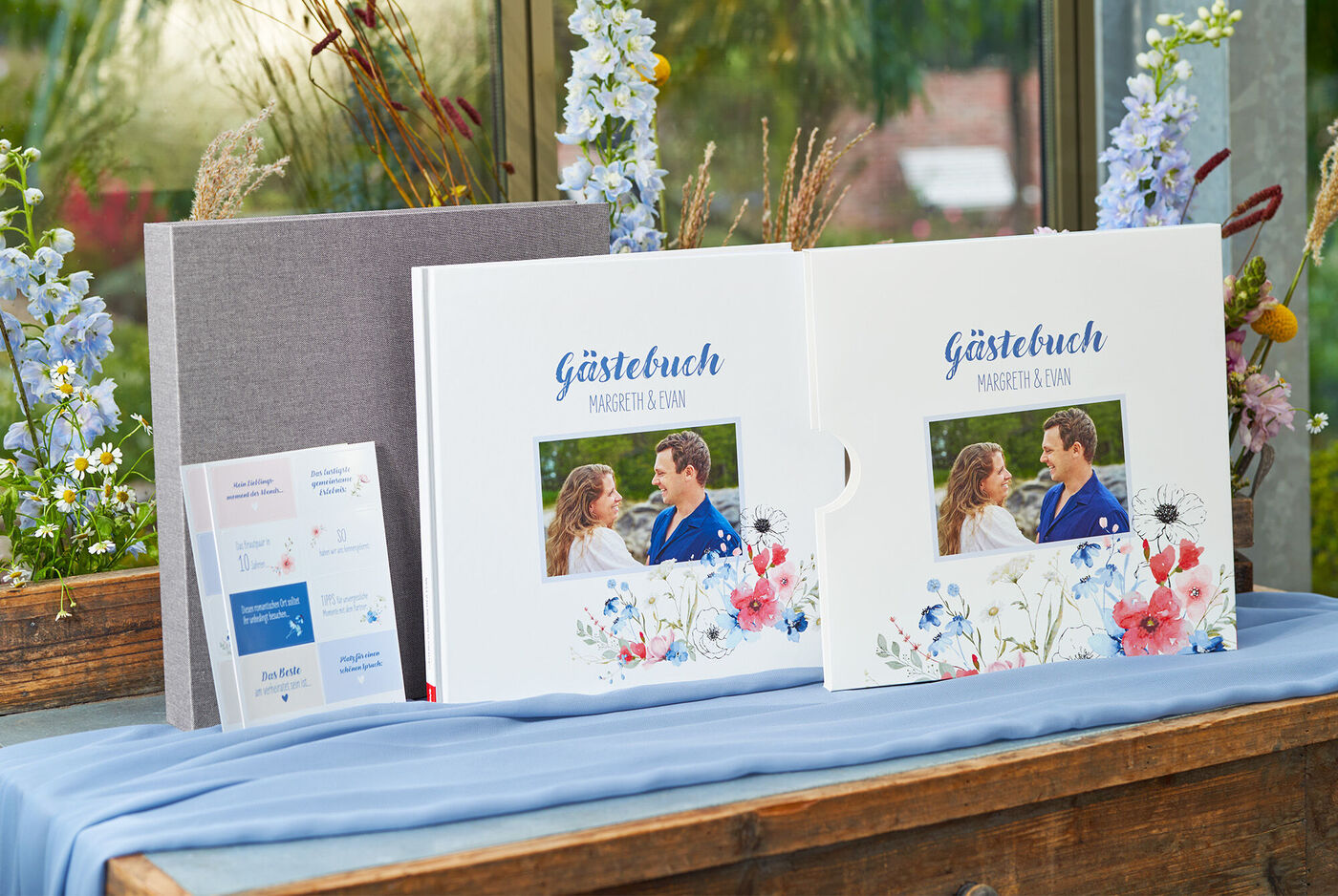 Zwei wunderschöne Gästebücher mit Blumenmuster auf einem Tisch, umgeben von floralen Dekorationen.