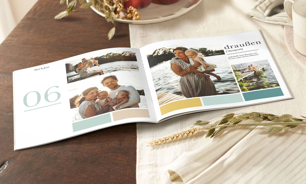 CEWE Fotobuch auf einem Tisch mit Naturmotiven und Familienfotos