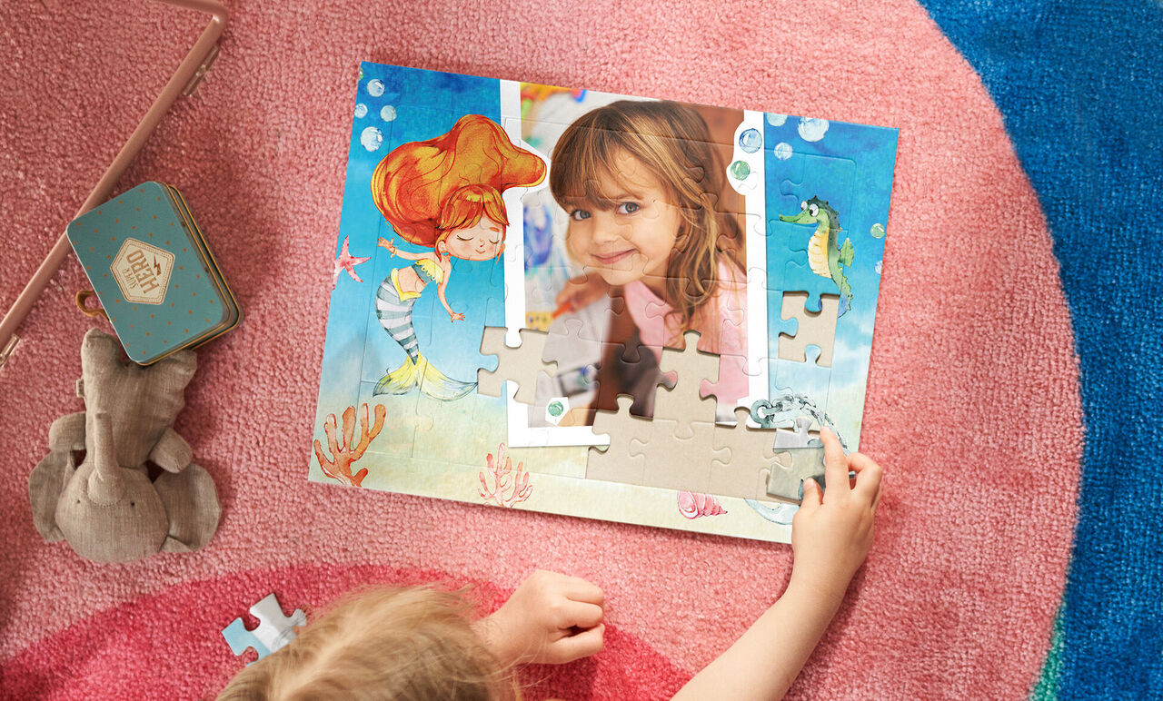 Ein Kind puzzelt ein farbenfrohes Bild mit einer Meerjungfrau und bunten Unterwasserwesen