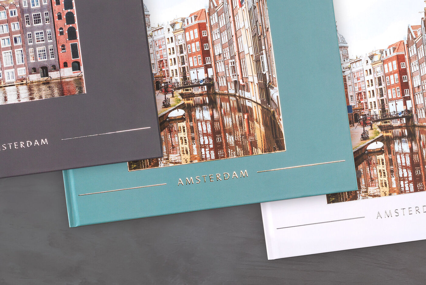 Drei verschiedene CEWE Fotobücher mit Amsterdam Motiv an einem Tisch