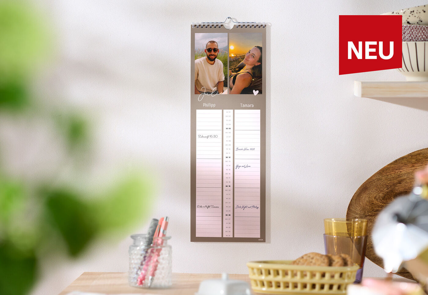 CEWE Fotokalender mit zwei Familienbildern hängt in heller Küche
