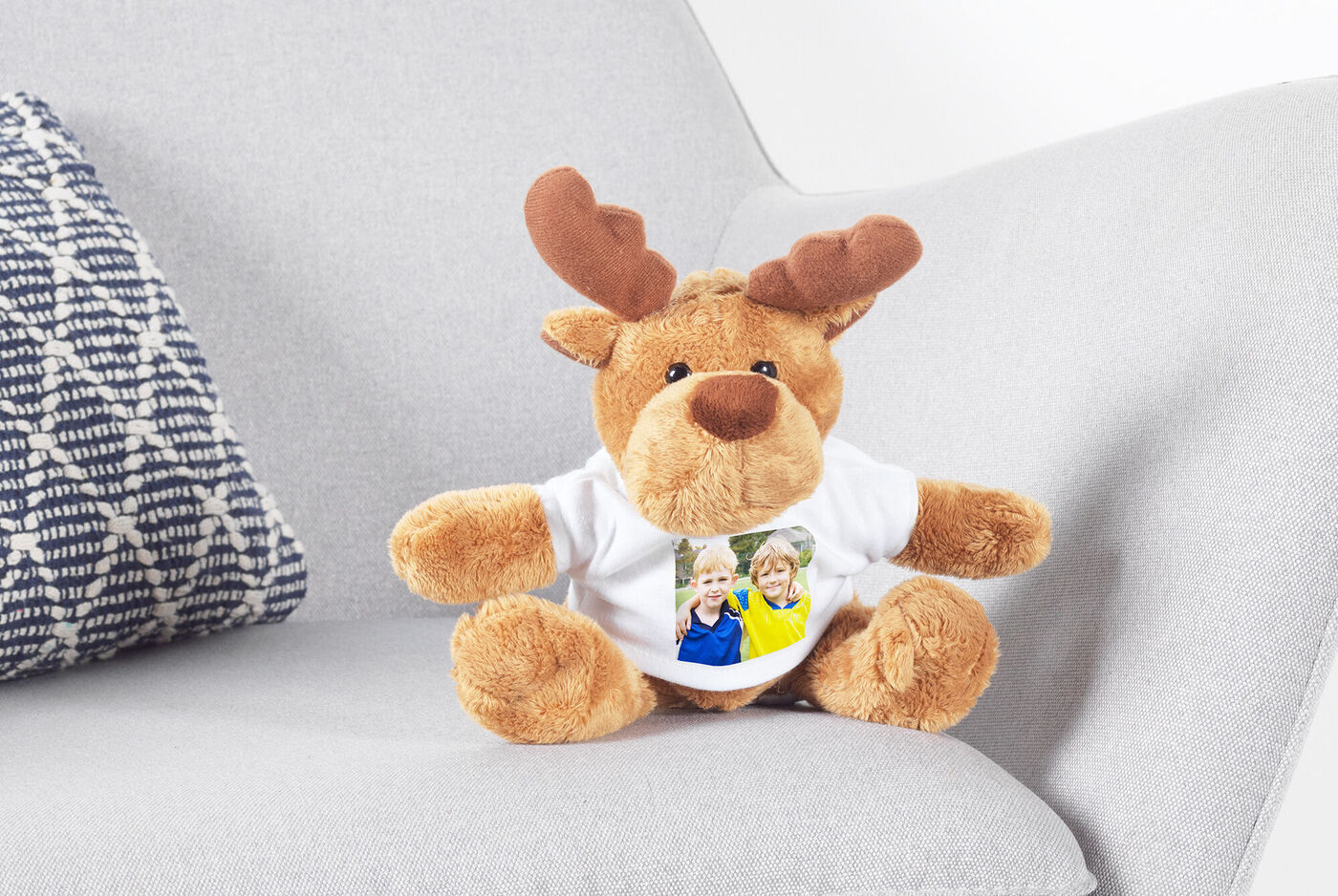 Ein kuscheliges Stoffrentier mit einem Foto von zwei Kindern auf einem weißen T-Shirt