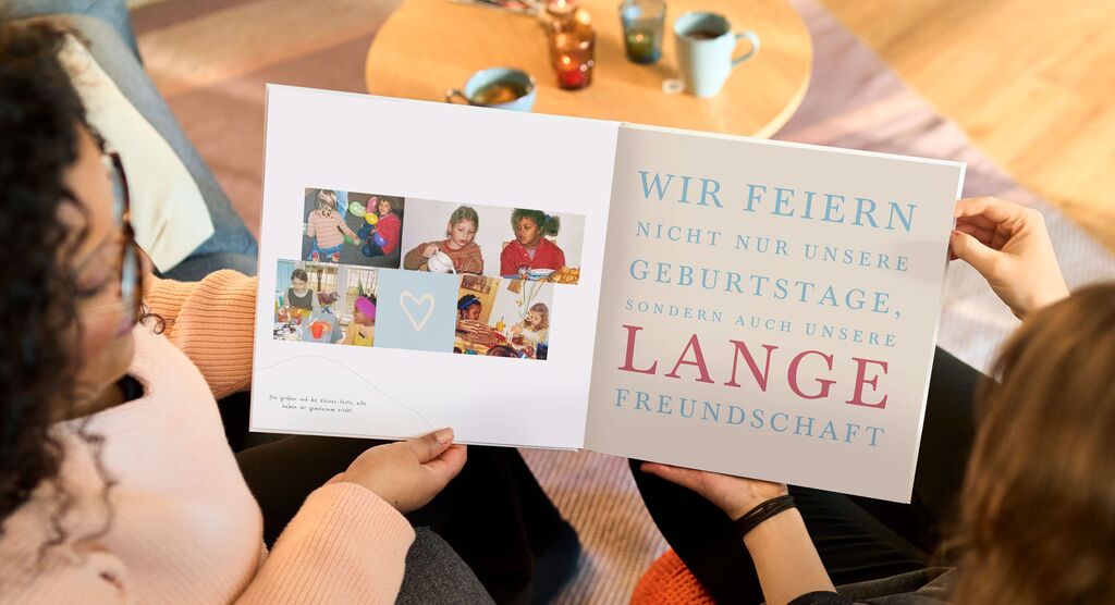 Zwei Personen blättern in einem CEWE Fotobuch mit Freude und feiern schöne Erinnerungen.