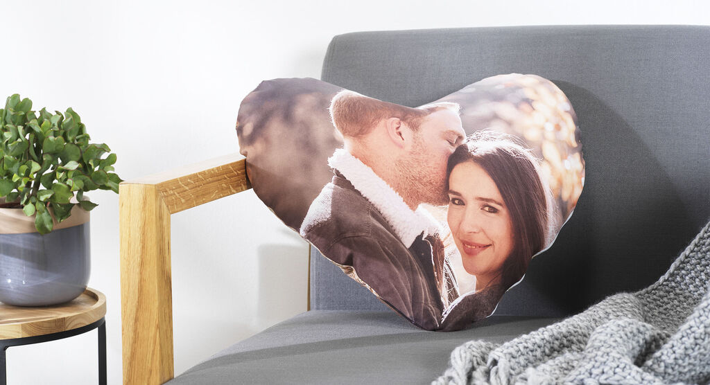 Herzförmiges Kissen mit einem romantischen Foto von einem Liebespaar.