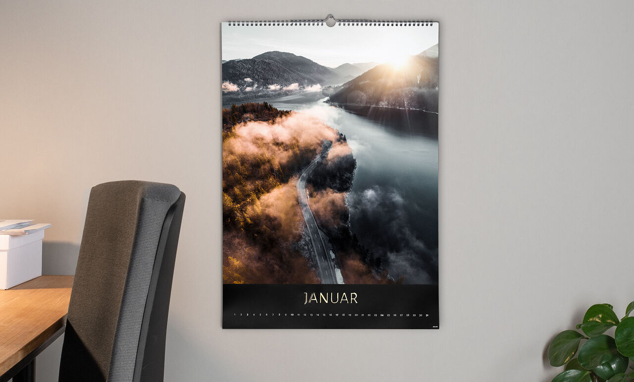 Kalenderblatt von Januar mit atemberaubendem Blick auf verschneite Berge und einen ruhigen Fluss.