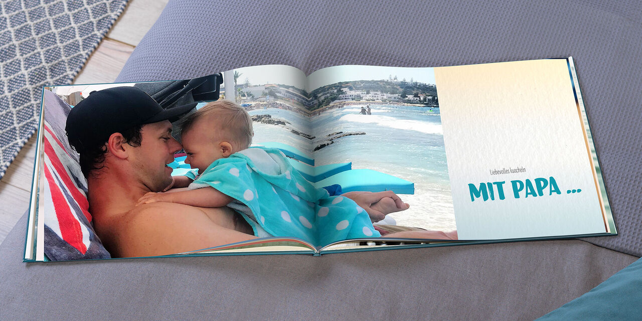 Ein Kind kuschelt mit seinem Vater am Strand in einem CEWE FOTOBUCH