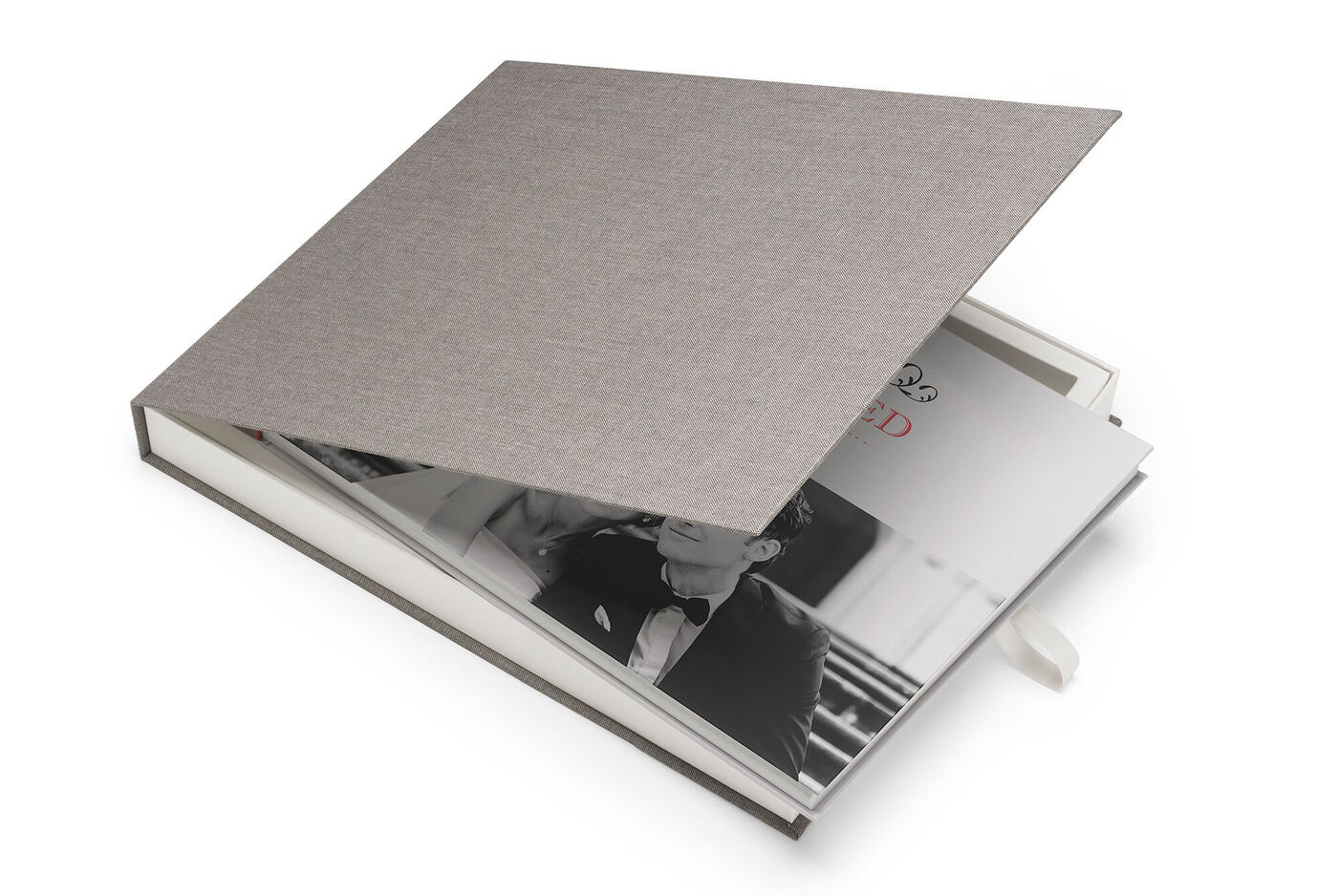 Ein geöffnetes CEWE FOTOBUCH mit einer eleganten grauen Hardcover-Hülle und einem romantischen Schwarz-Weiß-Foto auf der Innenseite
