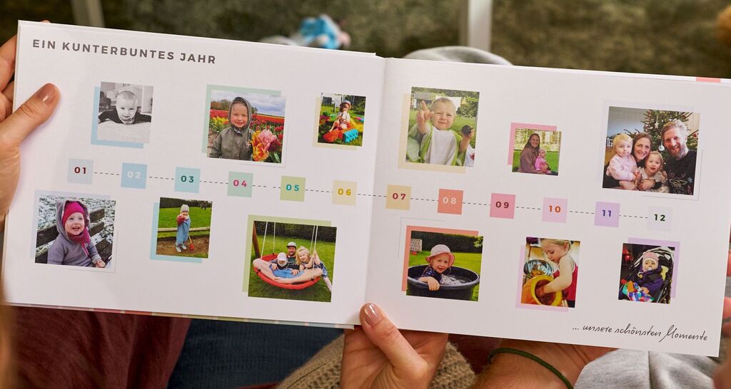 Zwei Personen halten ein geöffnetes CEWE FOTOBUCH mit einem bunten Zeitstrahl des Jahres.