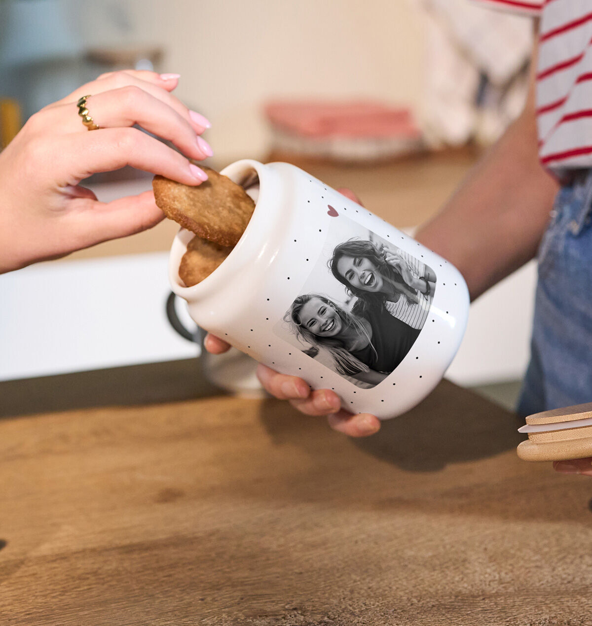 Eine CEWE Keksdose mit persönlichem Foto wird geöffnet und eine Hand nimmt einen Keks heraus.