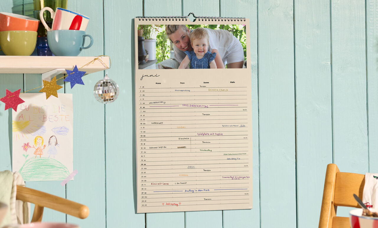 CEWE Fotokalender mit Familienfoto und handschriftlich eingetragenen Terminen an einer Küchenwand