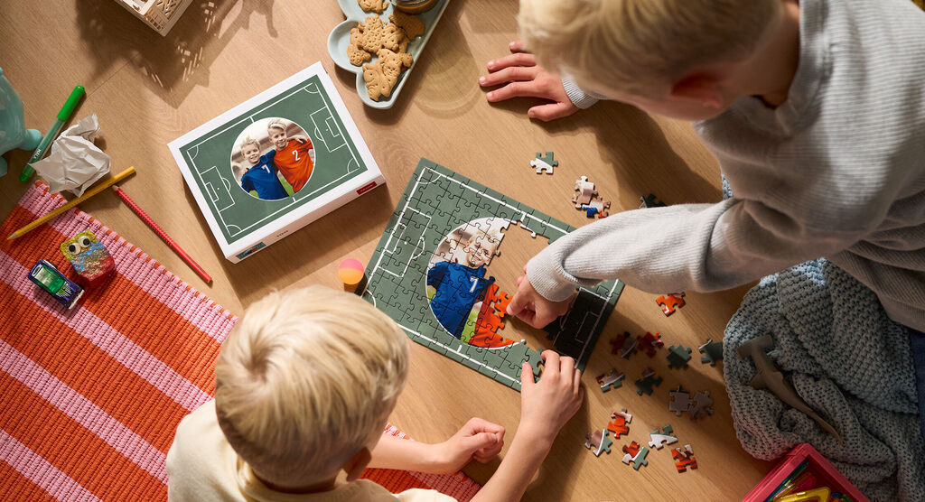 Zwei Kinder legen gemeinsam ein Puzzle mit einem personalisierten Motiv.