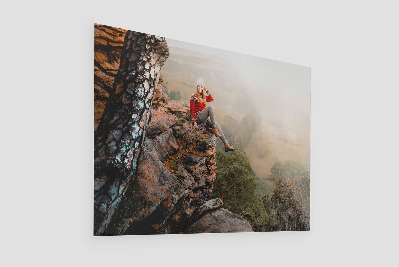 Eine Frau sitzt auf einem Felsen in der Natur und genießt die Aussicht