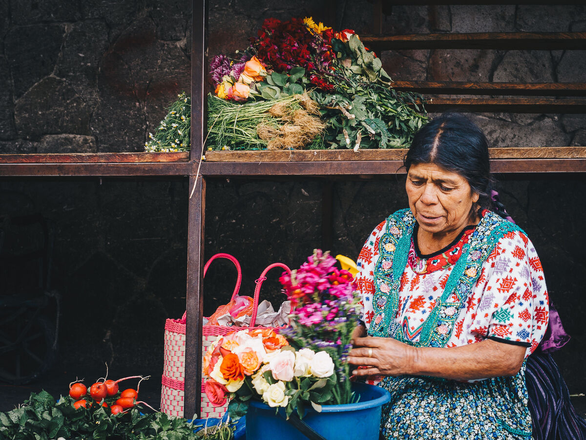 Begeisterte Marktverkäuferin mit bunten Blumenarrangements